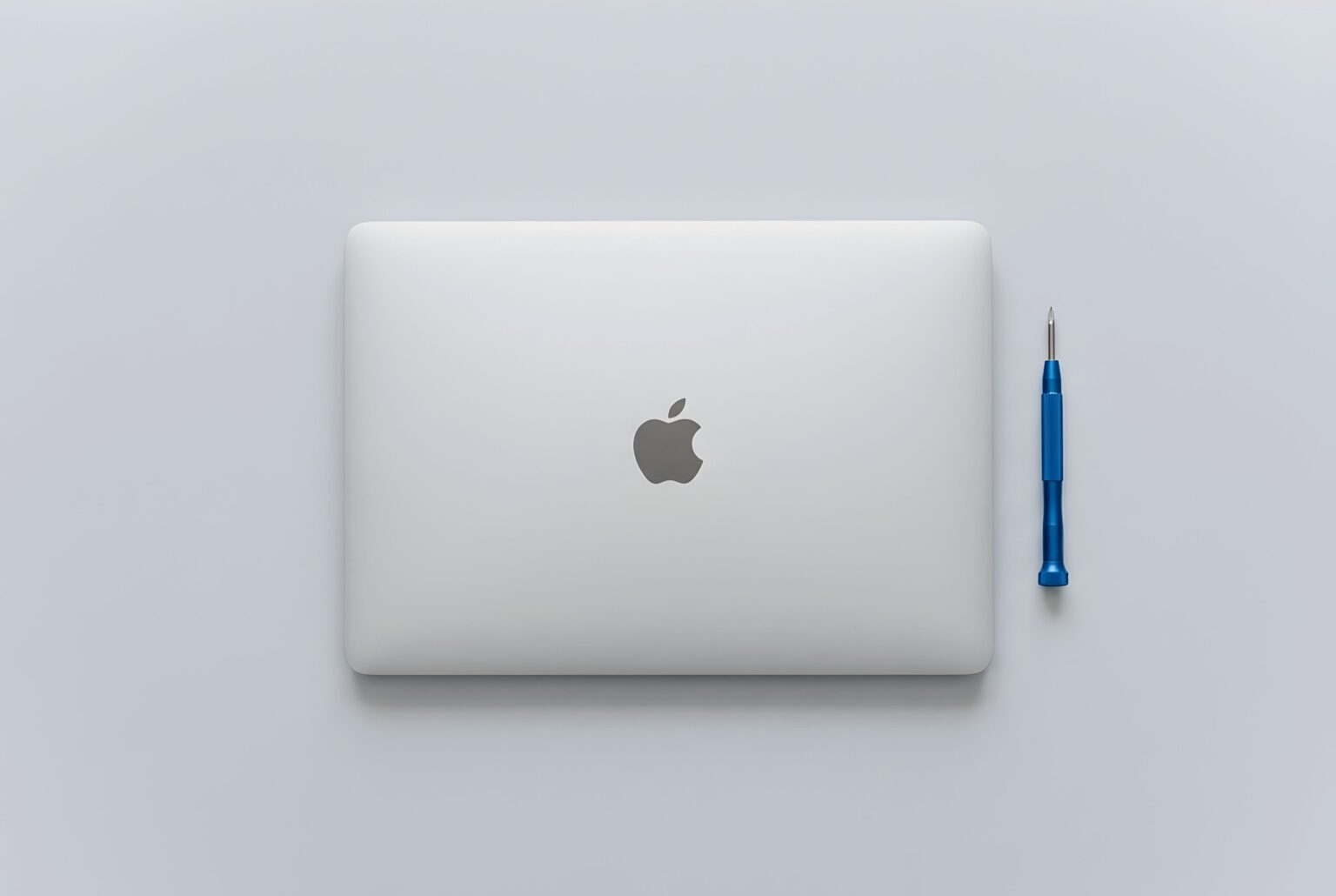 Geschlossenes MacBook mit blauem Feinschraubendreher, Managed Workplace von Landtwing